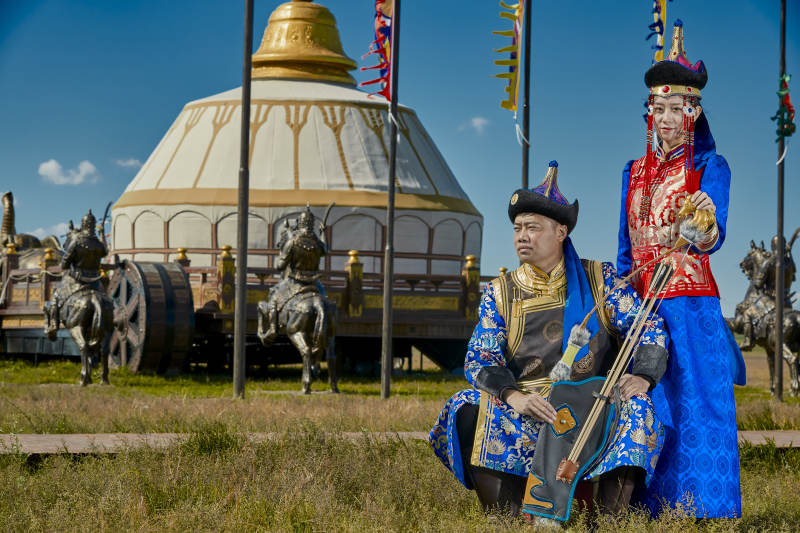草原上蒙古包前穿蒙古族传统服饰的年轻夫妻图片