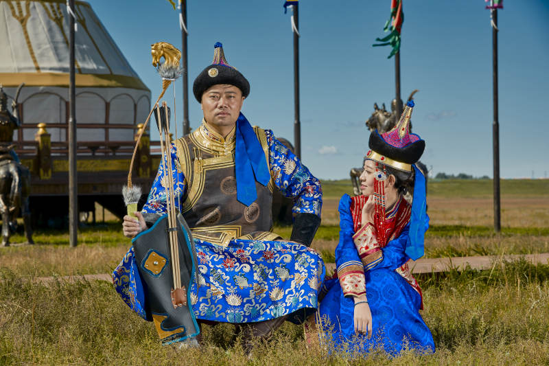草原上蒙古包前穿蒙古族传统服饰的年轻夫妻图片