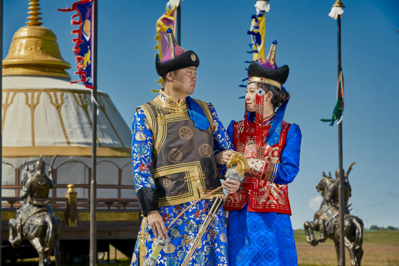 草原上蒙古包前穿蒙古族传统服饰的年轻夫妻图片