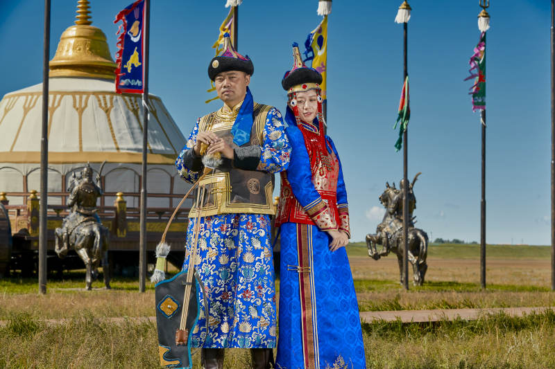草原上蒙古包前穿蒙古族传统服饰的年轻夫妻图片