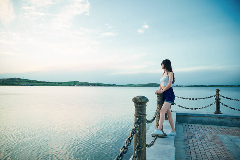 盛夏夕阳晚霞湖边码头看风景的少女图片