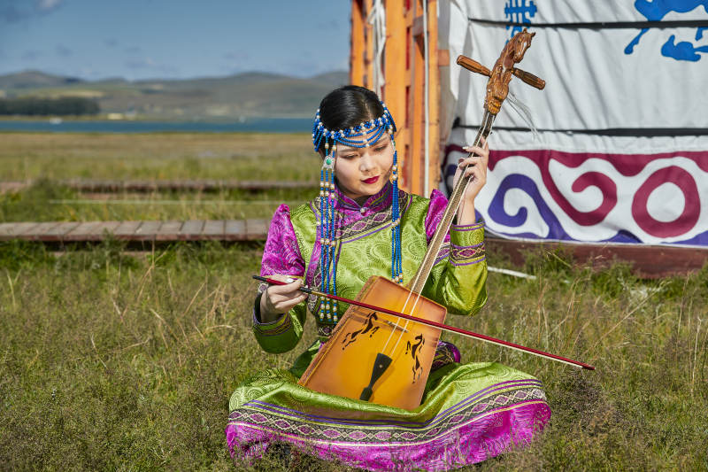 蒙古包前穿蒙古族服饰拉马头琴的蒙族女乐手图片