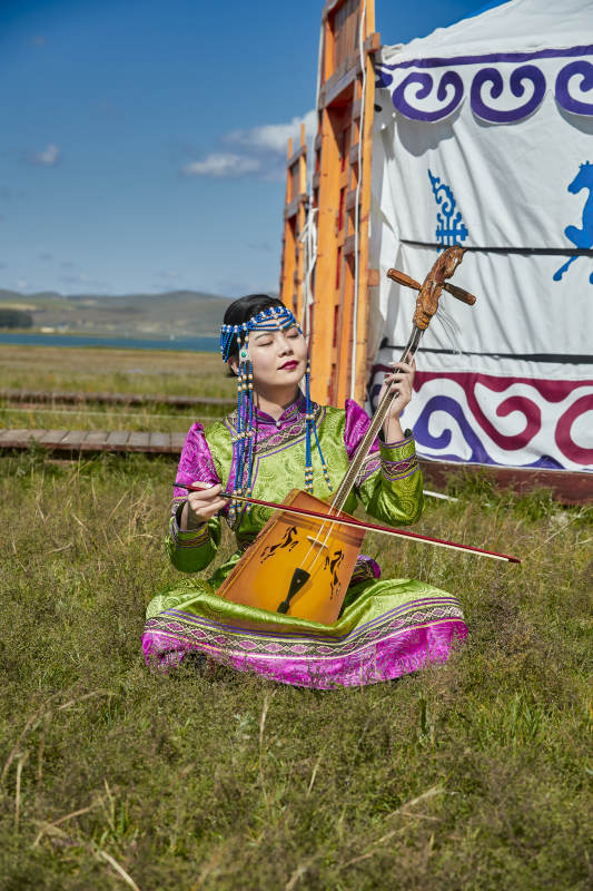 蒙古包前穿蒙古族服饰拉马头琴的蒙族女乐手图片