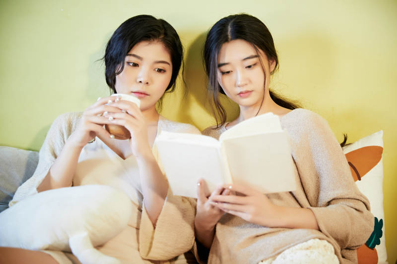 坐在床上读书的俩位美女图片