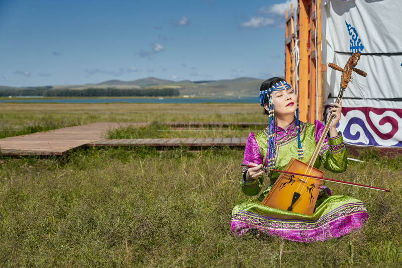 蒙古包前穿蒙古族服饰拉马头琴的蒙族女乐手图片