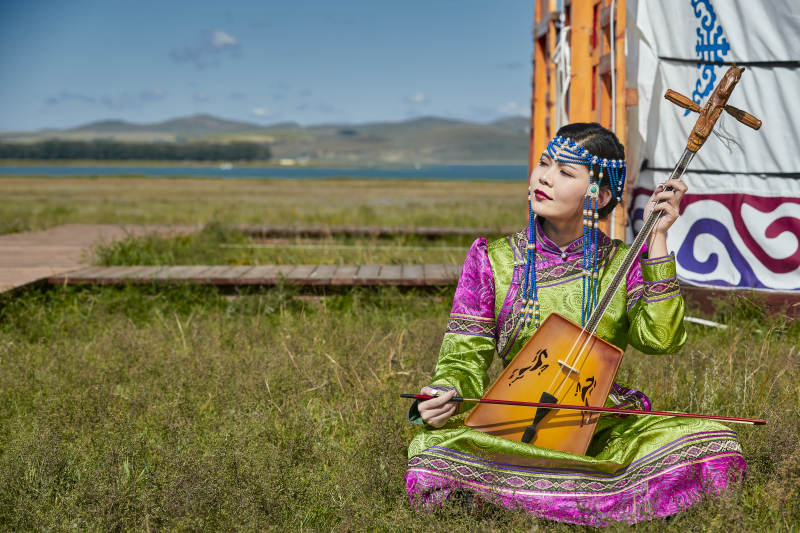 蒙古包前穿蒙古族服饰拉马头琴的蒙族女乐手图片