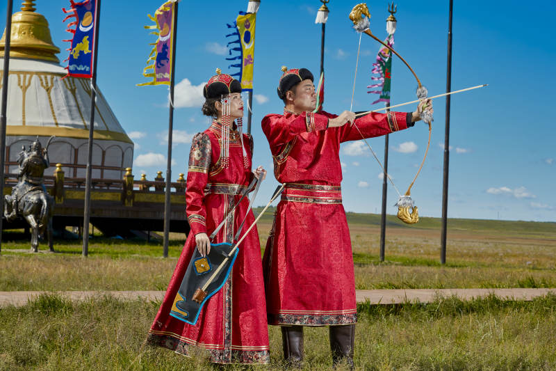 草原上蒙古包前穿蒙古族传统服饰的年轻夫妻图片