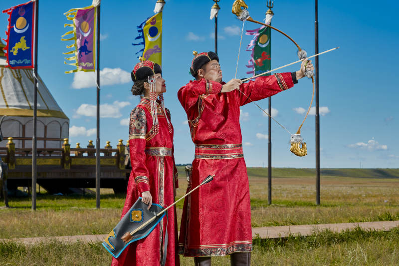 草原上蒙古包前穿蒙古族传统服饰的年轻夫妻图片