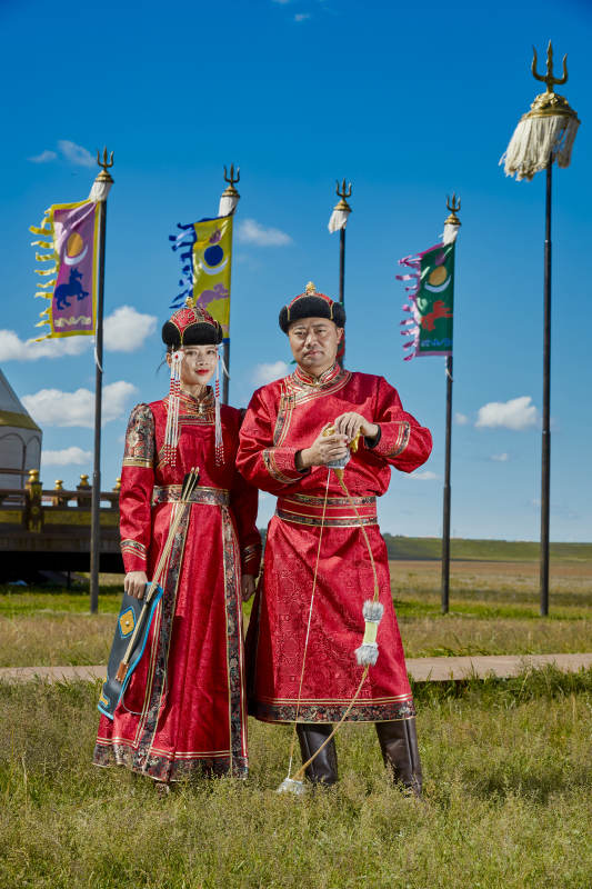 草原上蒙古包前穿蒙古族传统服饰的年轻夫妻图片