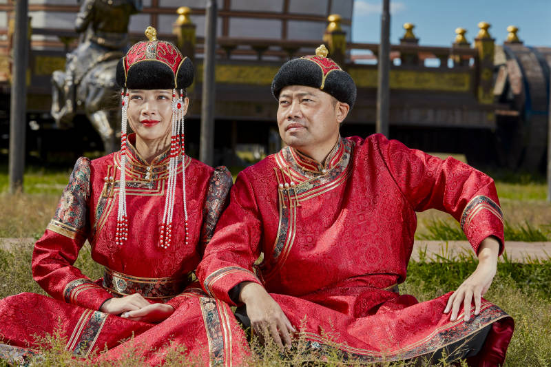 草原上蒙古包前穿蒙古族传统服饰的年轻夫妻图片
