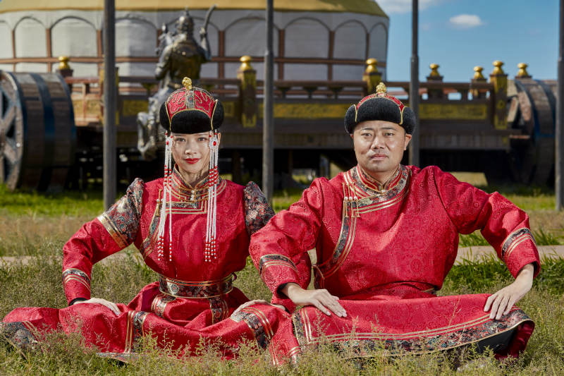 草原上蒙古包前穿蒙古族传统服饰的年轻夫妻图片