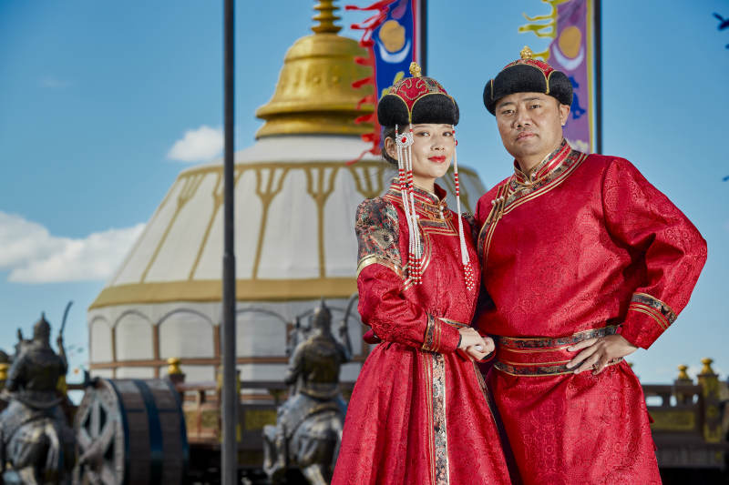 草原上蒙古包前穿蒙古族传统服饰的年轻夫妻图片