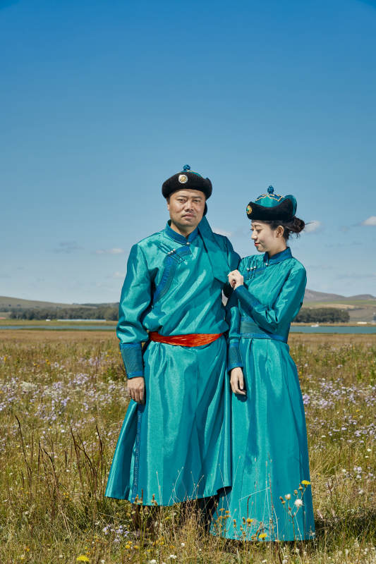 草原上蒙古包前穿蒙古族传统服饰的年轻夫妻图片