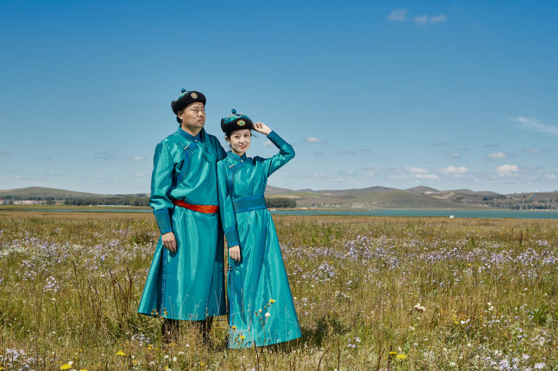 草原上蒙古包前穿蒙古族传统服饰的年轻夫妻图片