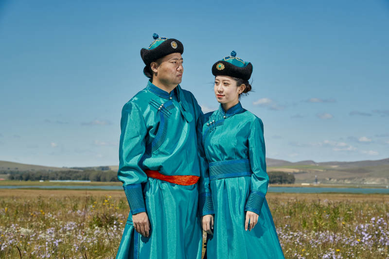 草原上蒙古包前穿蒙古族传统服饰的年轻夫妻图片