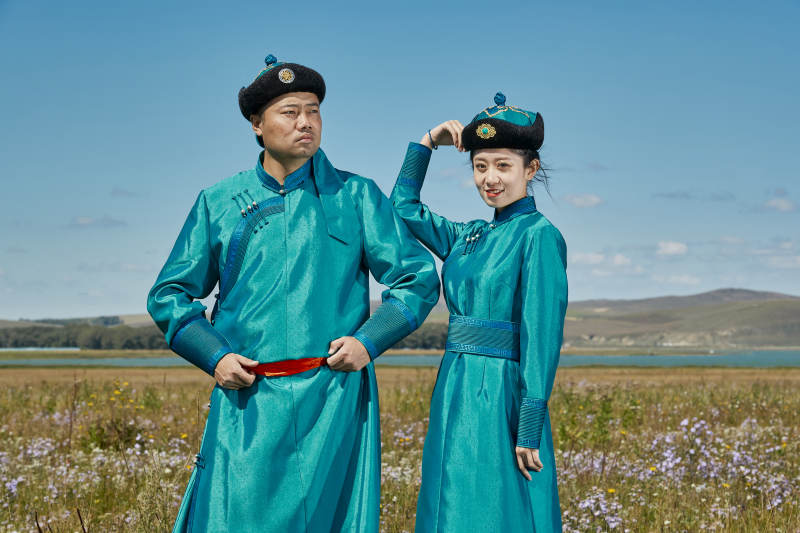草原上蒙古包前穿蒙古族传统服饰的年轻夫妻图片