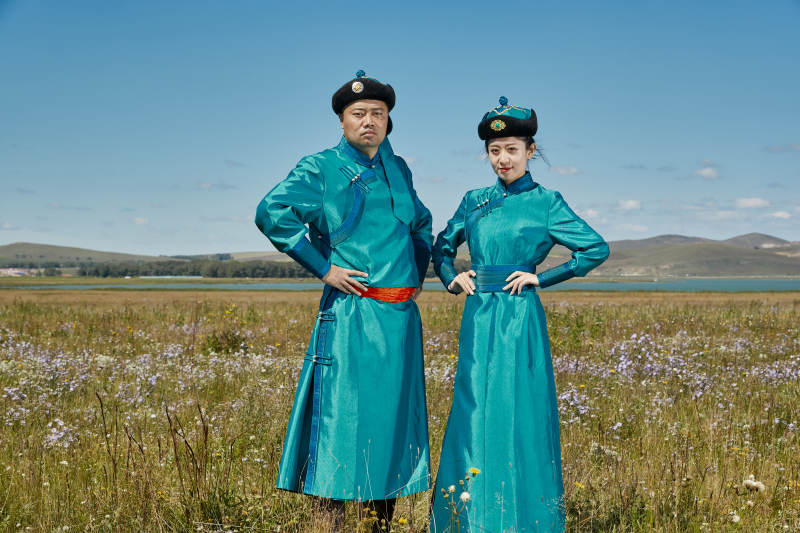 草原上蒙古包前穿蒙古族传统服饰的年轻夫妻图片