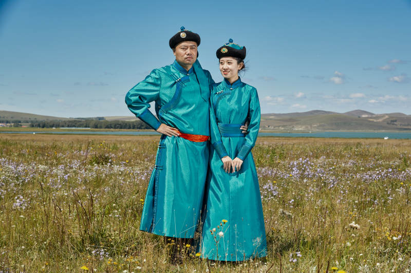 草原上蒙古包前穿蒙古族传统服饰的年轻夫妻图片