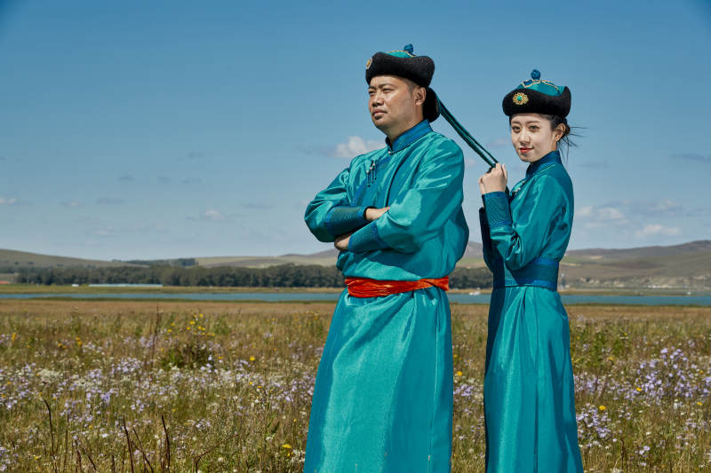 草原上蒙古包前穿蒙古族传统服饰的年轻夫妻图片