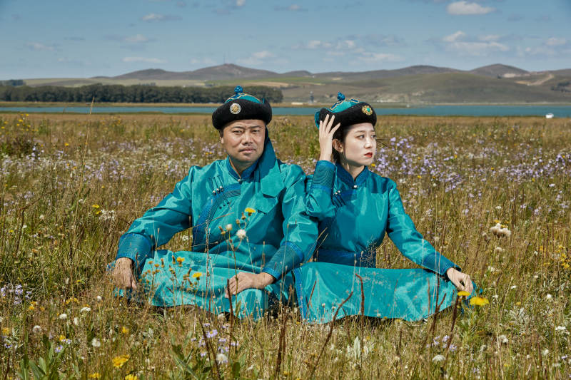 草原上蒙古包前穿蒙古族传统服饰的年轻夫妻图片