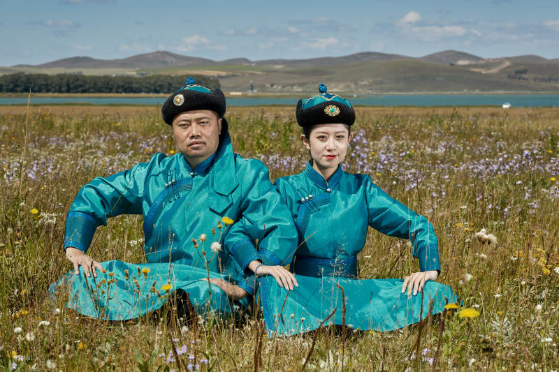 草原上蒙古包前穿蒙古族传统服饰的年轻夫妻图片