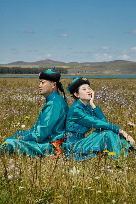 草原上蒙古包前穿蒙古族传统服饰的年轻夫妻图片