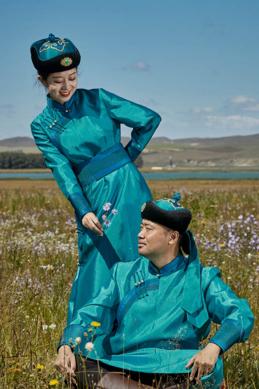 草原上蒙古包前穿蒙古族传统服饰的年轻夫妻图片
