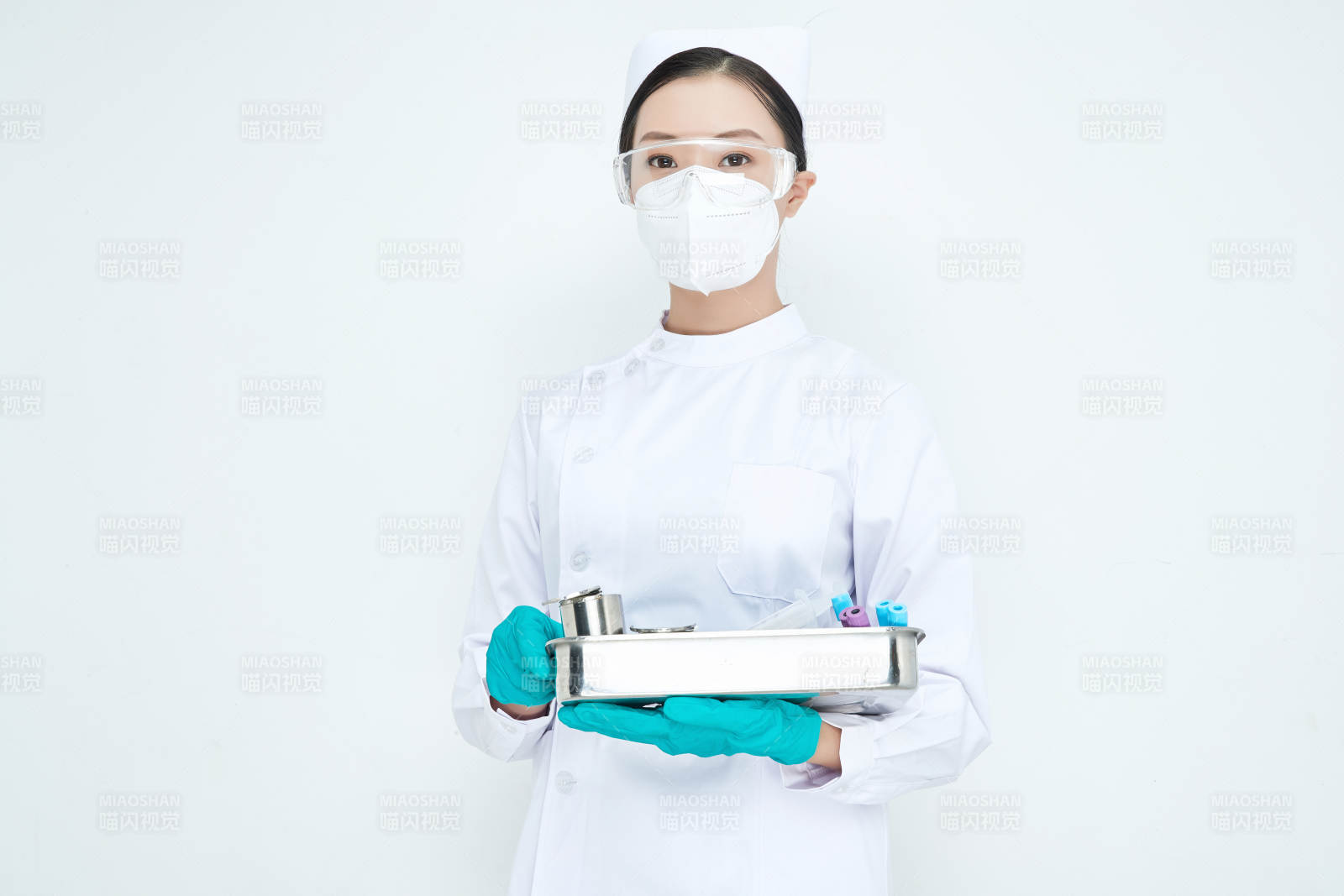 身穿护士服手抱化验托盘的年轻女护士图片