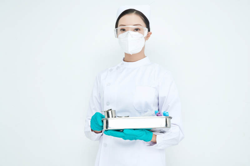 身穿护士服手抱化验托盘的年轻女护士图片