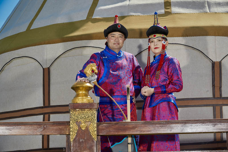 草原上蒙古包前穿蒙古族传统服饰的年轻夫妻图片