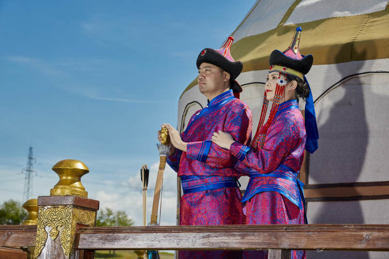 草原上蒙古包前穿蒙古族传统服饰的年轻夫妻图片