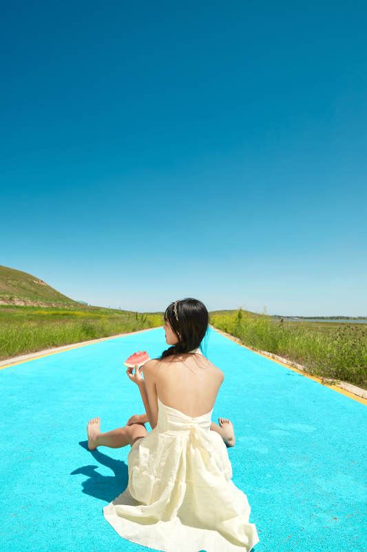 夏日户外湖边彩色公路上玩耍吃西瓜的少女图片