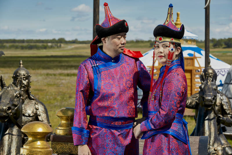草原上蒙古包前穿蒙古族传统服饰的年轻夫妻图片