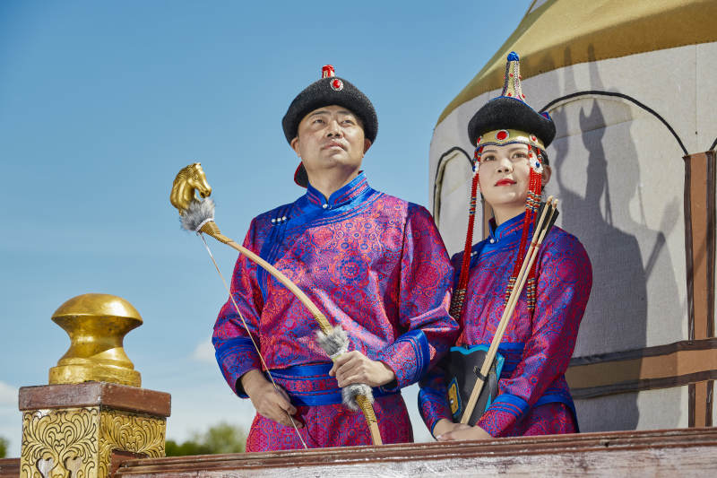 草原上蒙古包前穿蒙古族传统服饰的年轻夫妻图片