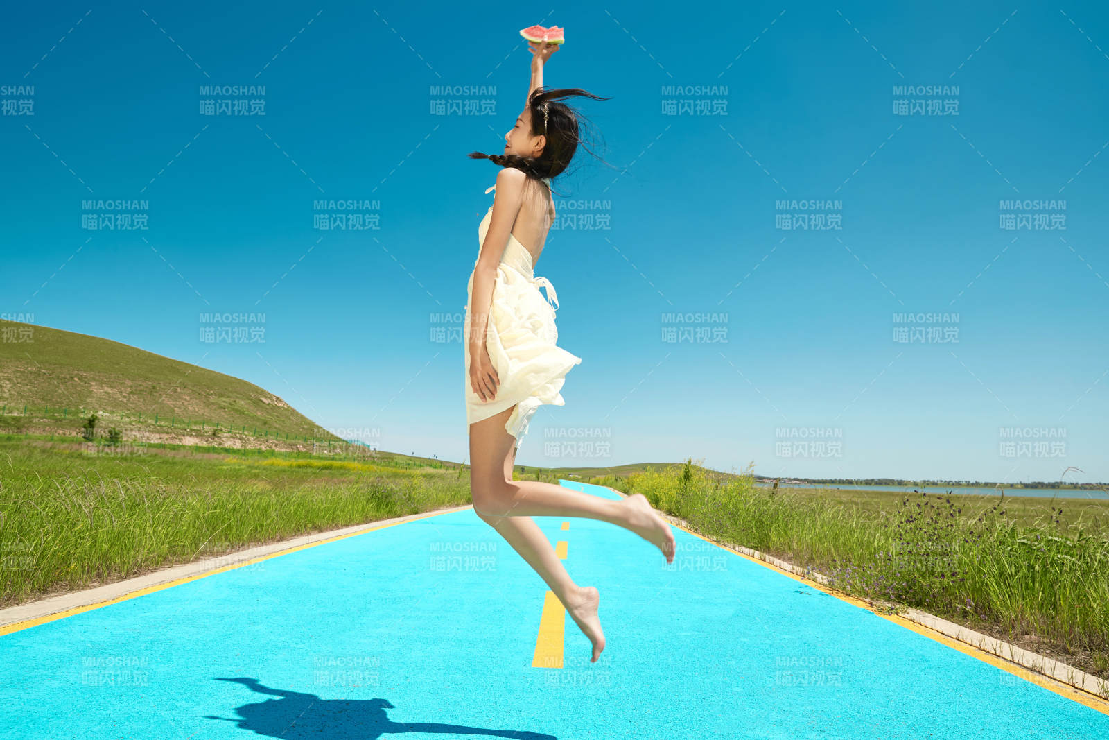 夏日户外湖边彩色公路上玩耍吃西瓜的少女图片