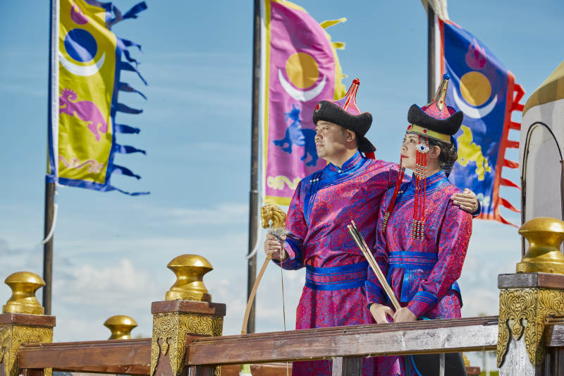 草原上蒙古包前穿蒙古族传统服饰的年轻夫妻图片