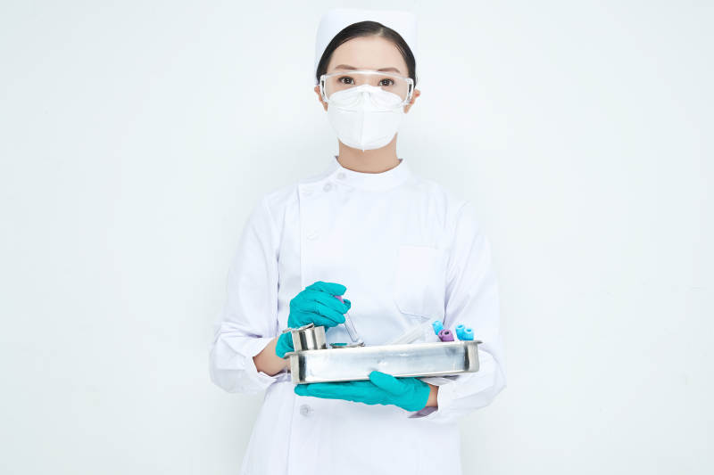 身穿护士服手抱化验托盘的年轻女护士图片