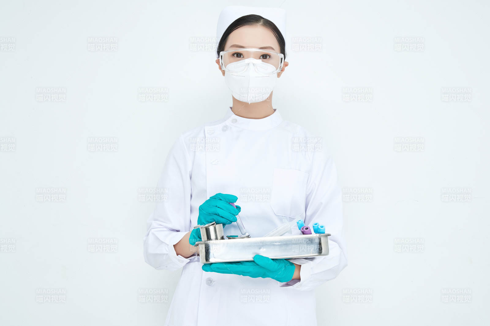 身穿护士服手抱化验托盘的年轻女护士图片