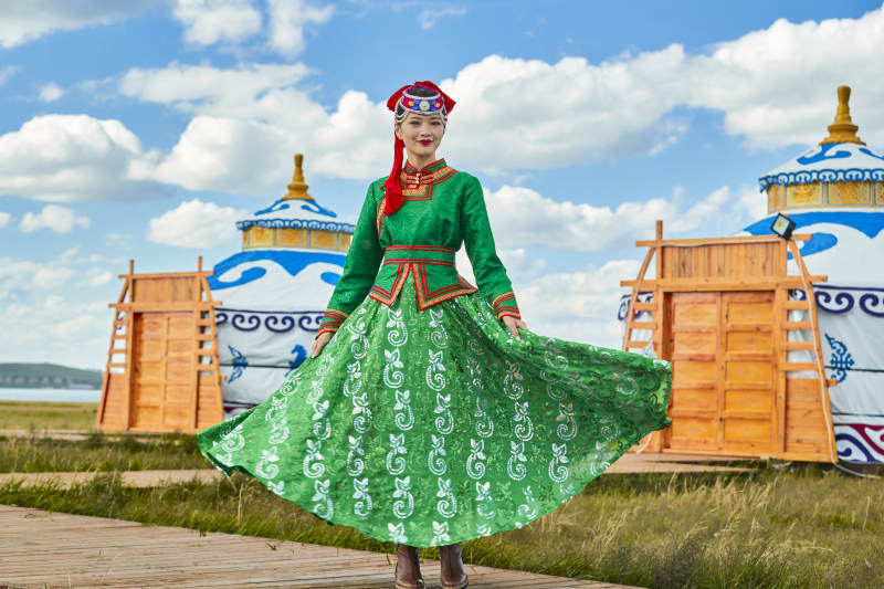 草原上穿着蒙古族传统服饰的亚洲年轻女性图片