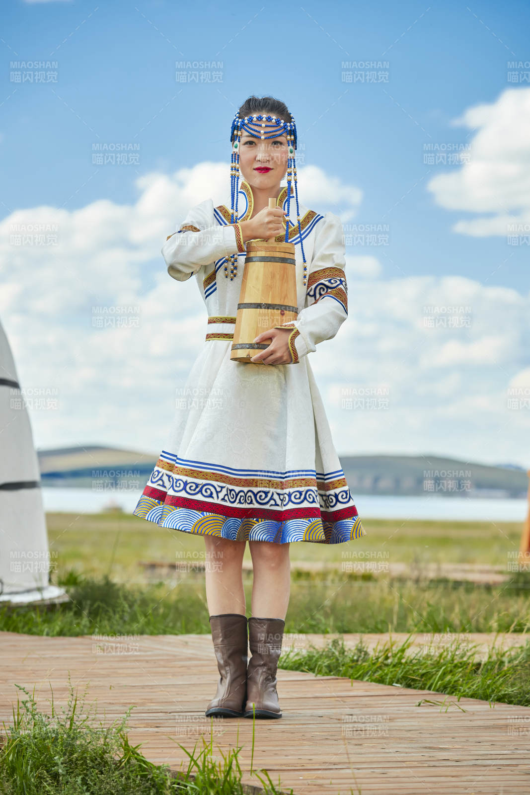 蒙古包前穿蒙古族饰怀抱奶茶桶的蒙族少女图片