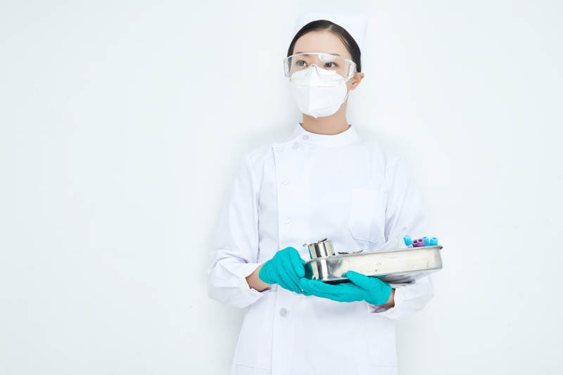 身穿护士服手抱化验托盘的年轻女护士图片