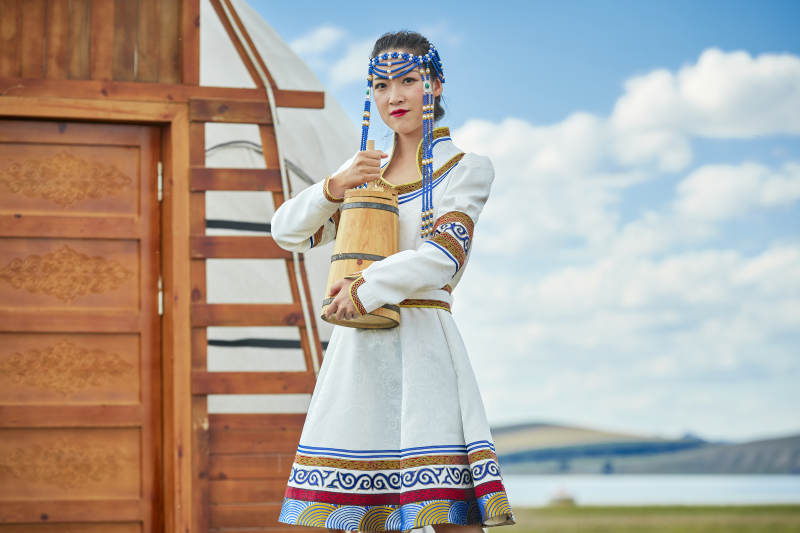 蒙古包前穿蒙古族饰怀抱奶茶桶的蒙族少女图片