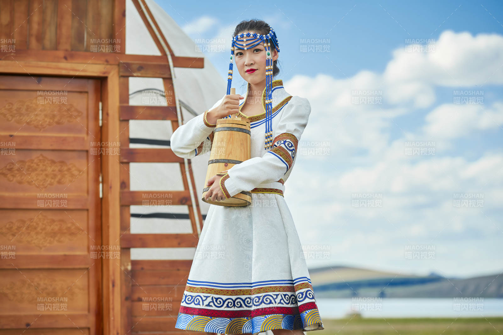 蒙古包前穿蒙古族饰怀抱奶茶桶的蒙族少女图片