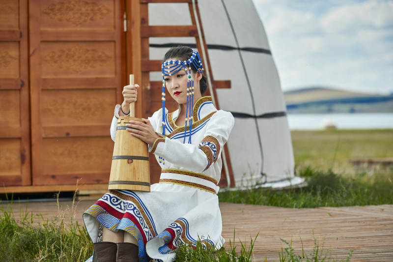 蒙古包前穿蒙古族饰怀抱奶茶桶的蒙族少女图片