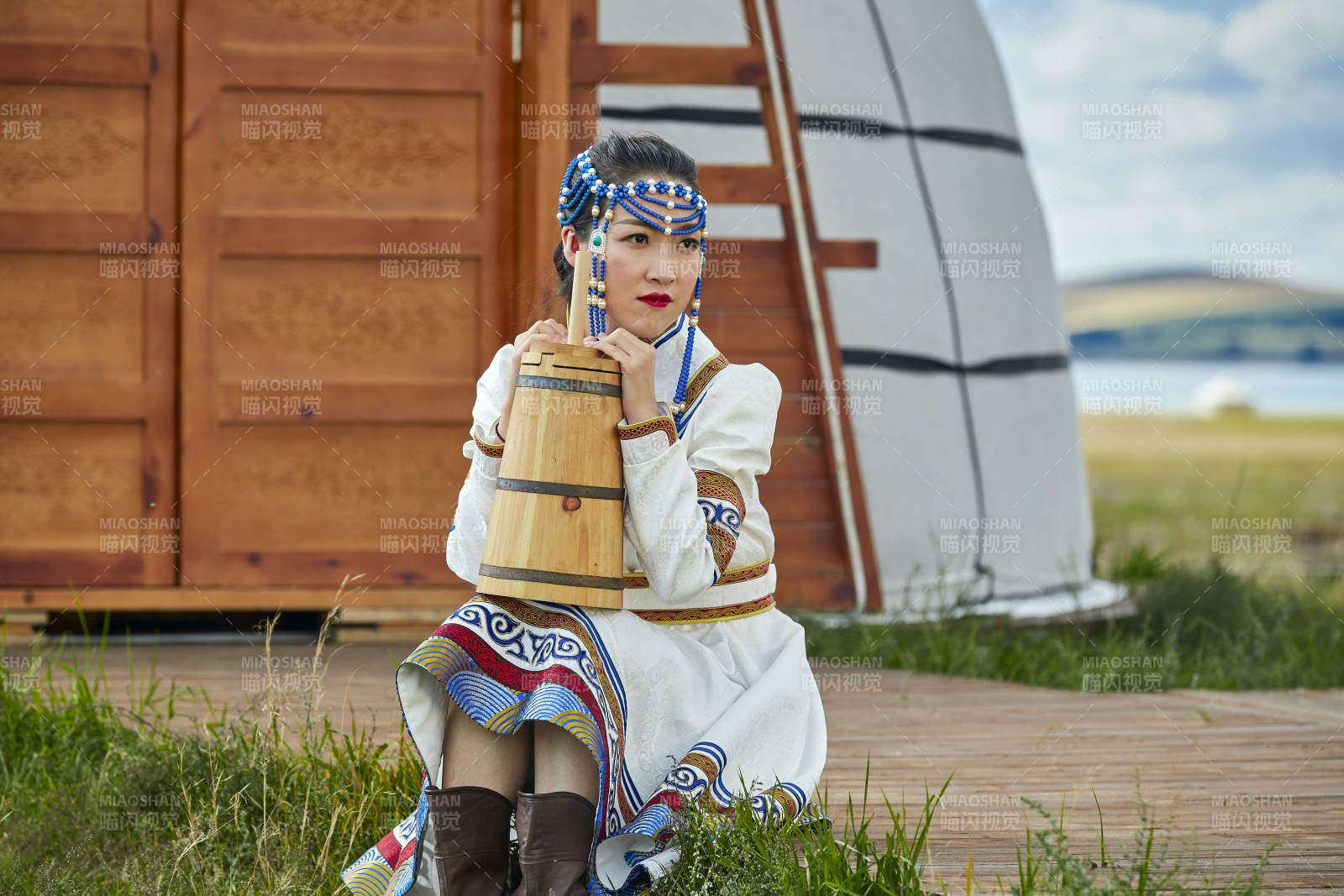 蒙古包前穿蒙古族饰怀抱奶茶桶的蒙族少女图片