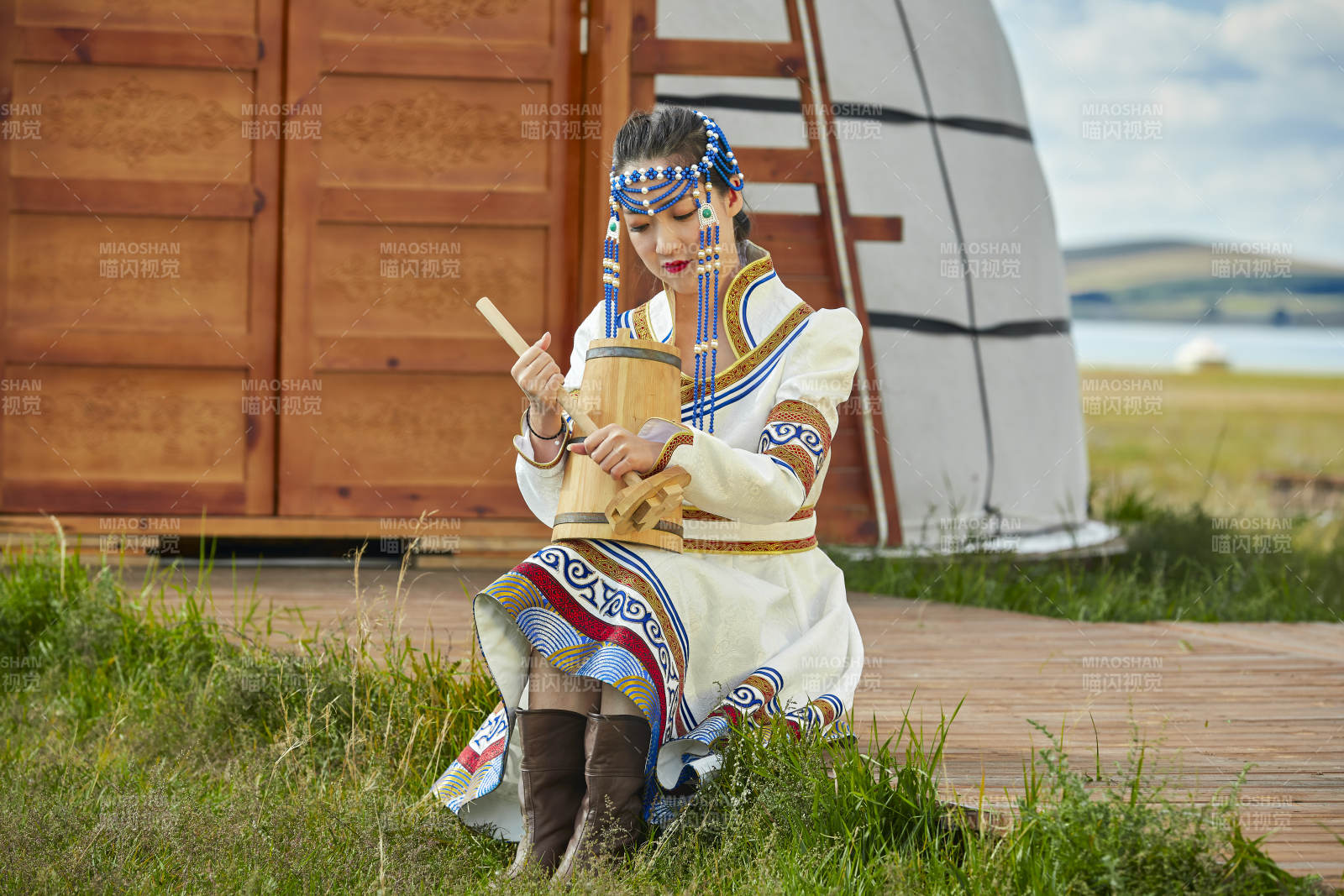 蒙古包前穿蒙古族饰怀抱奶茶桶的蒙族少女图片