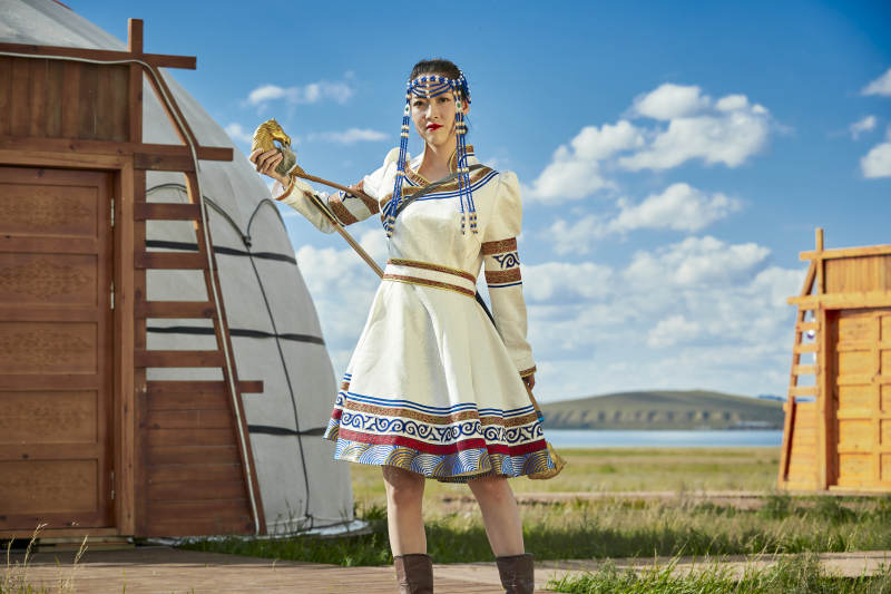 草原湖畔身穿蒙古族饰手持弓箭的蒙族少女图片