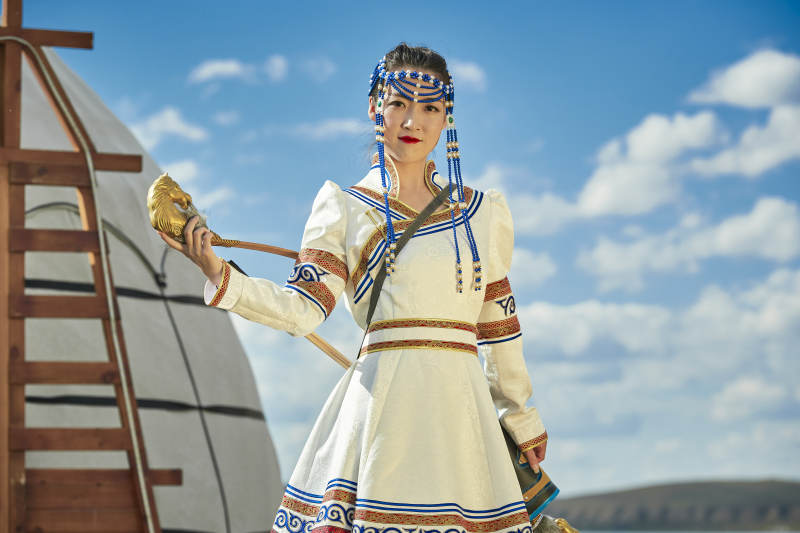 草原湖畔身穿蒙古族饰手持弓箭的蒙族少女图片