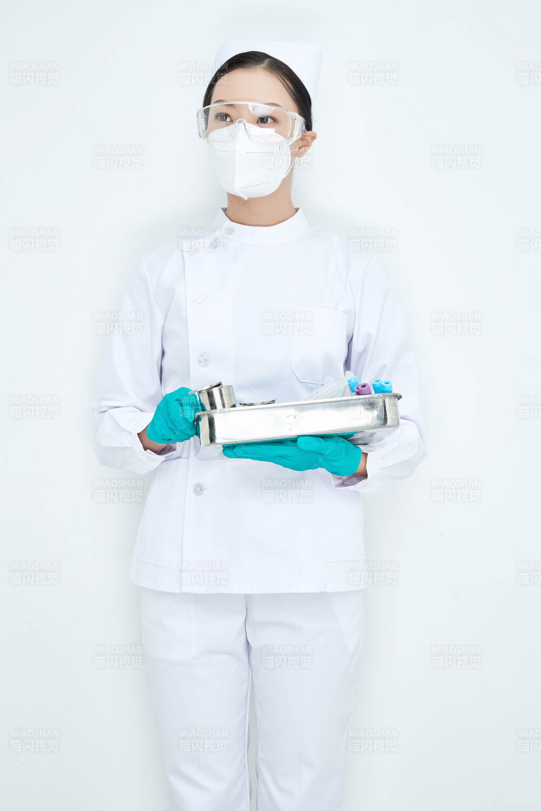 身穿护士服手抱化验托盘的年轻女护士图片