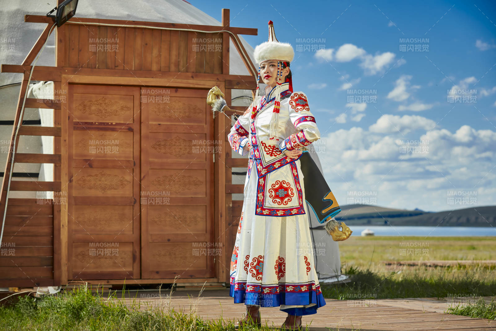 草原湖畔身穿蒙古族饰手持弓箭的蒙族少女图片